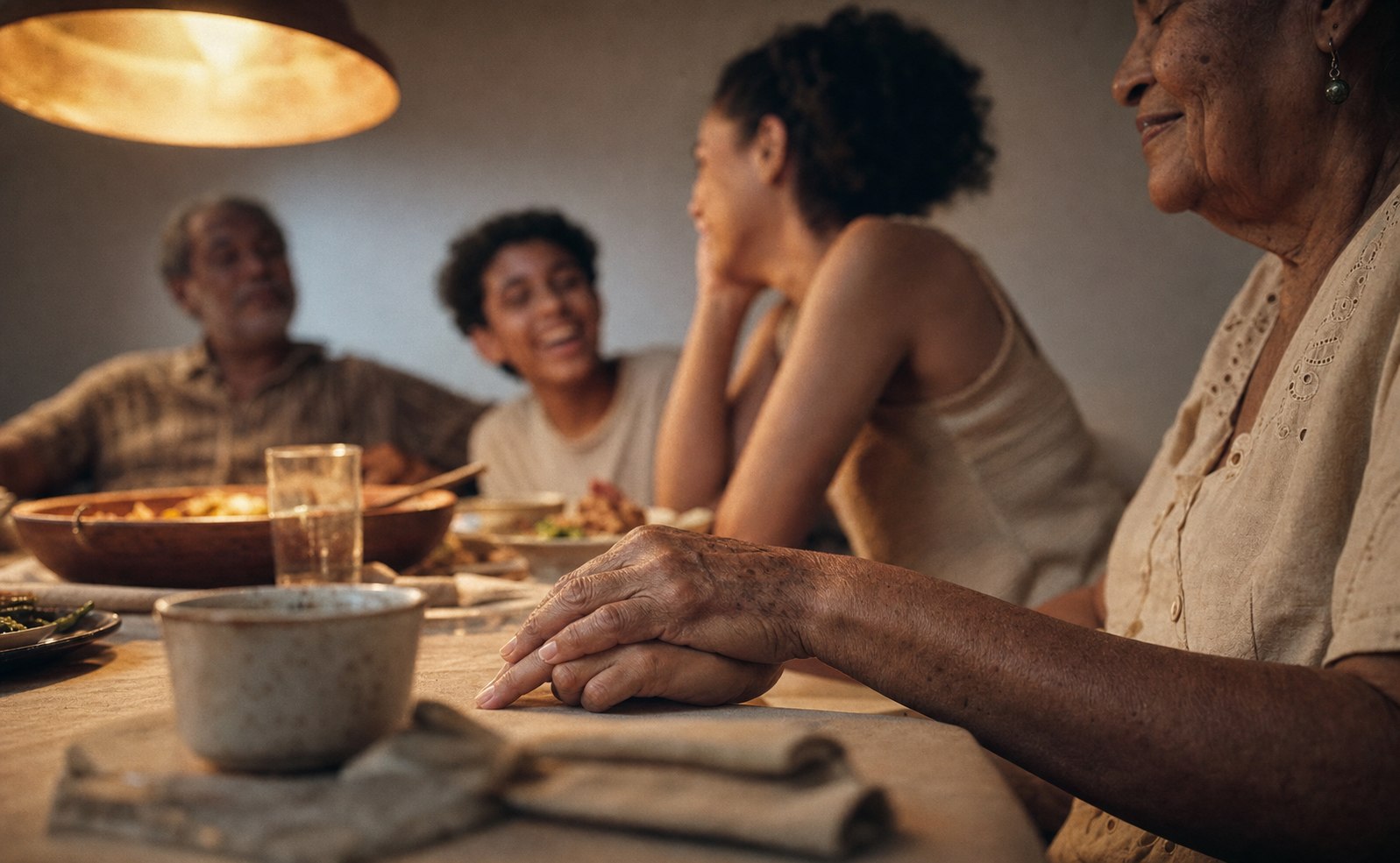 Três gerações de uma família à mesa, mãos sobrepostas